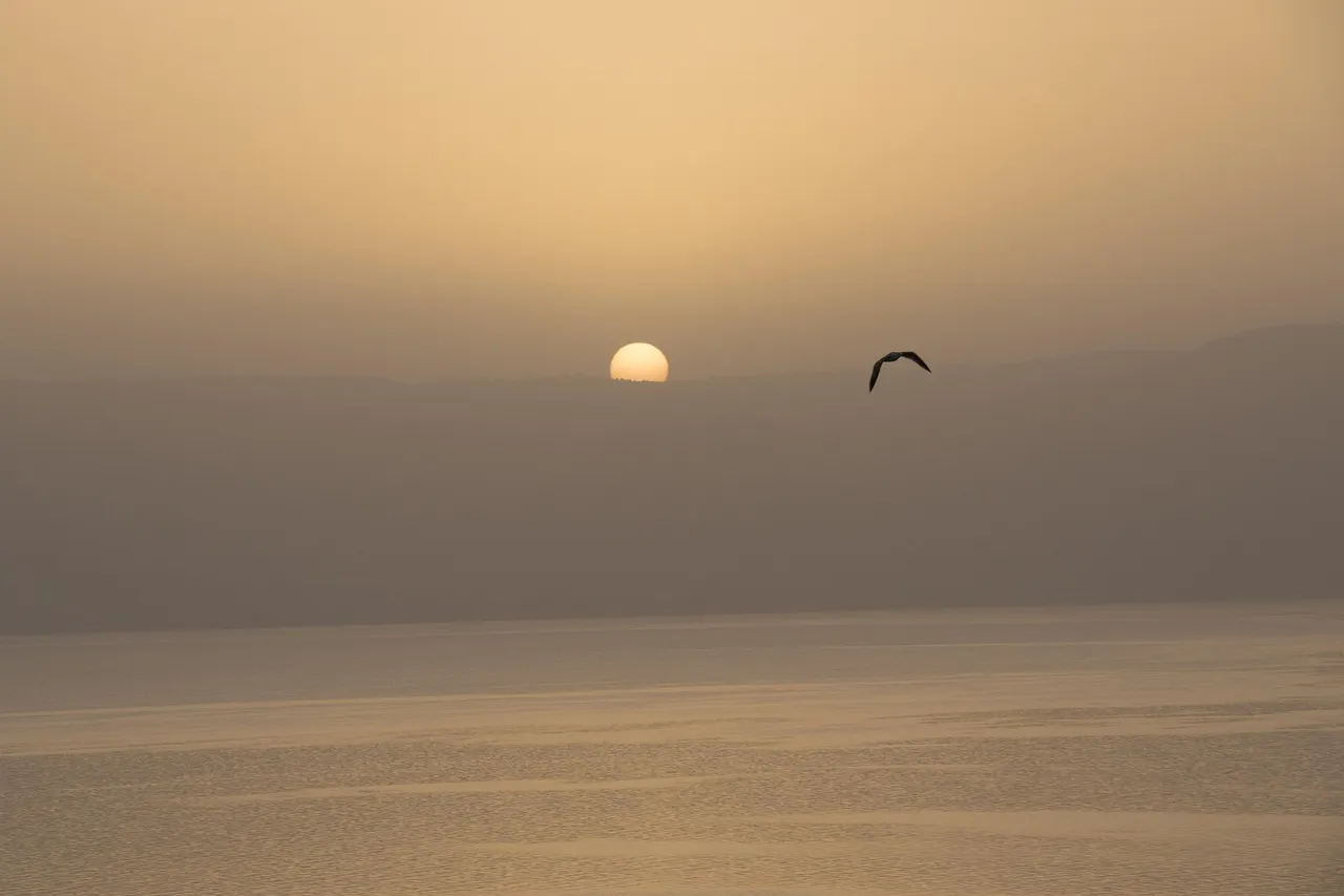 Sunrise over the Sea of Galilee with hills visible across the calm water