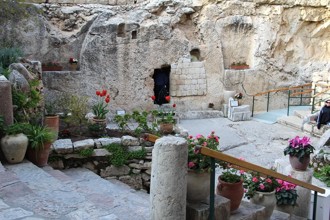 La tumba excavada en la roca y el jardín de la Tumba del Jardín en Jerusalén, con plantas en flor enmarcando la entrada a la cámara sepulcral