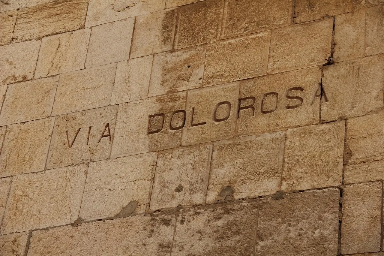 Peregrinos cargando una cruz de madera por las estrechas calles de piedra de la Vía Dolorosa en la Ciudad Vieja de Jerusalén